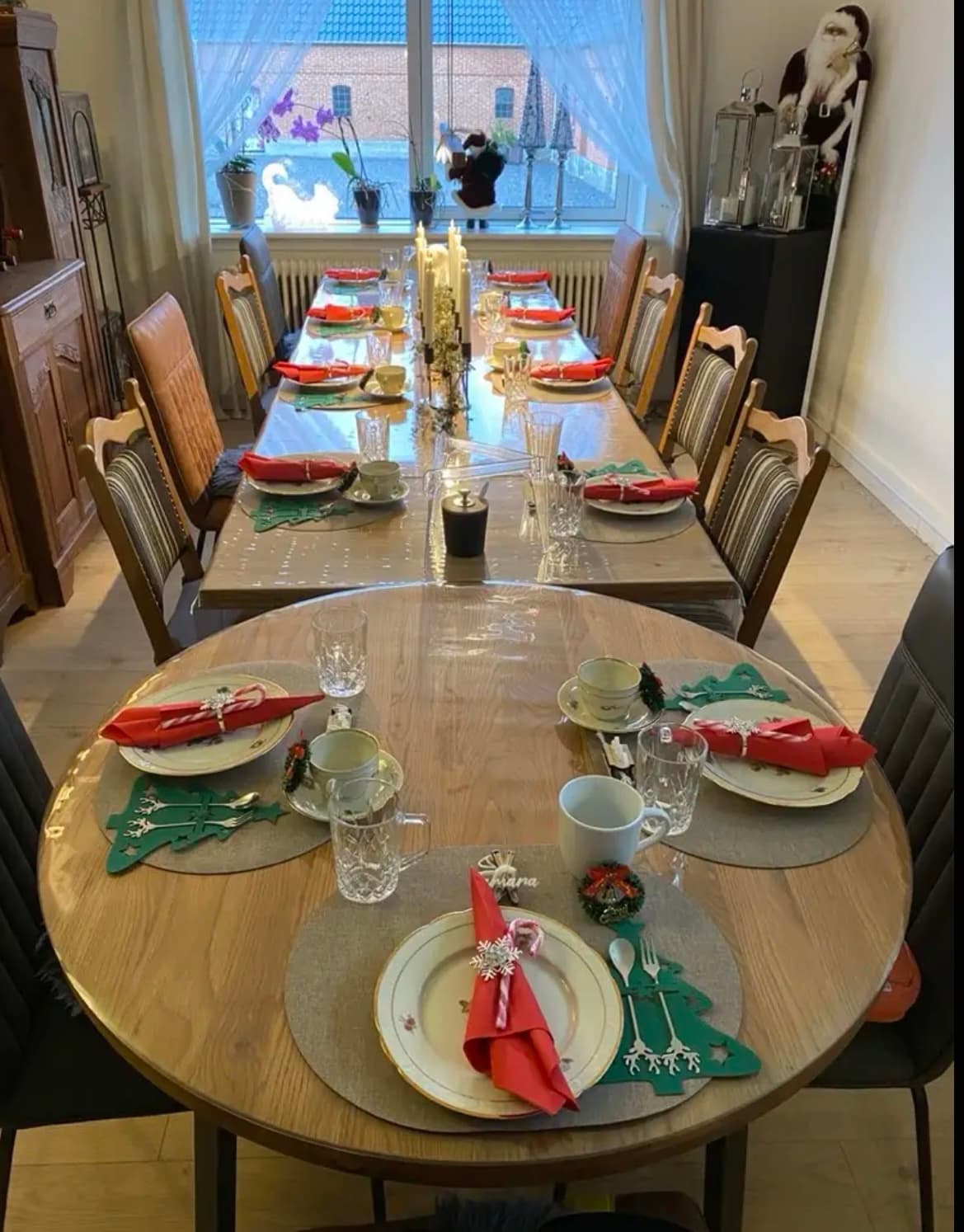 Christmas setting on an unfolded oak table; the tabletop under the red napkins is protected by a transparent mat