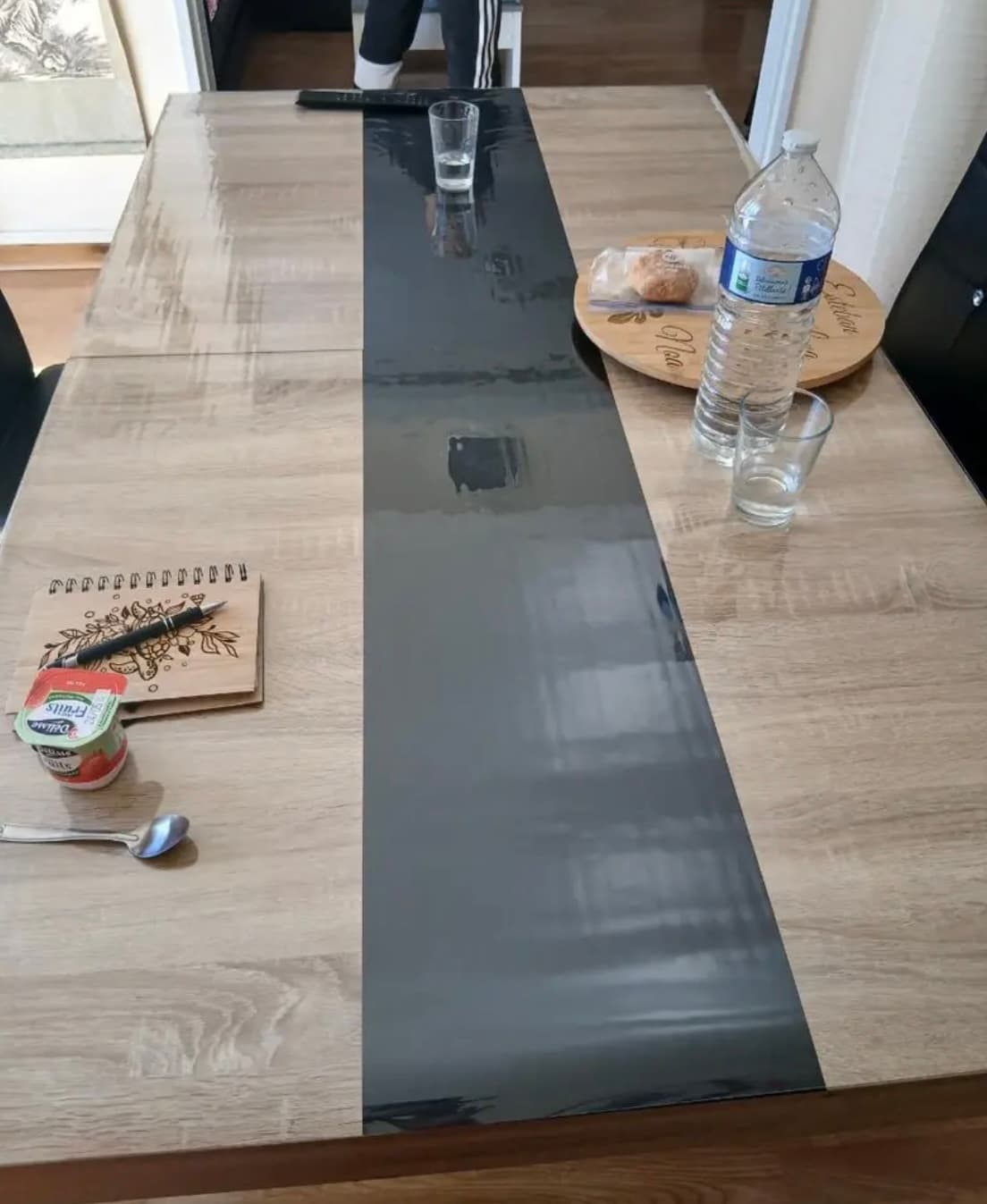 Breakfast on a long table with a graphite stripe: water, glasses, notebook - everything on the mat