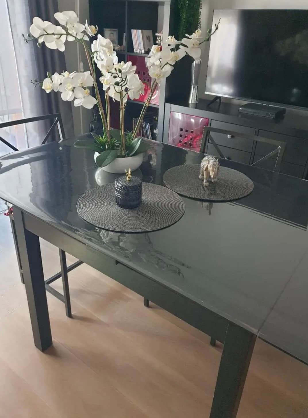 Graphite table in the living room with a white orchid and round placemats, top under a mat