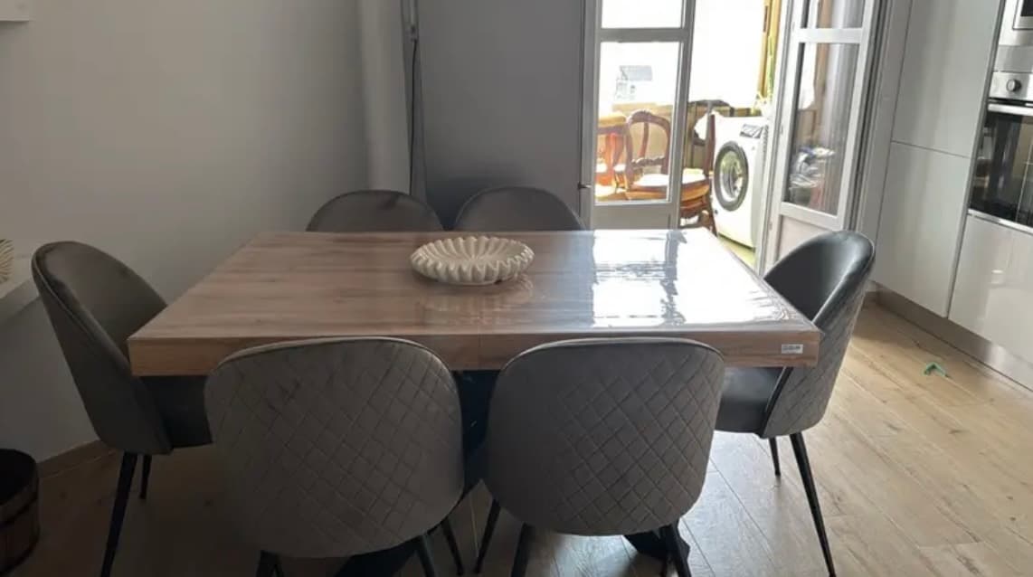 Kitchen table with six gray chairs; there is still a tag on the mat that has just been unfolded