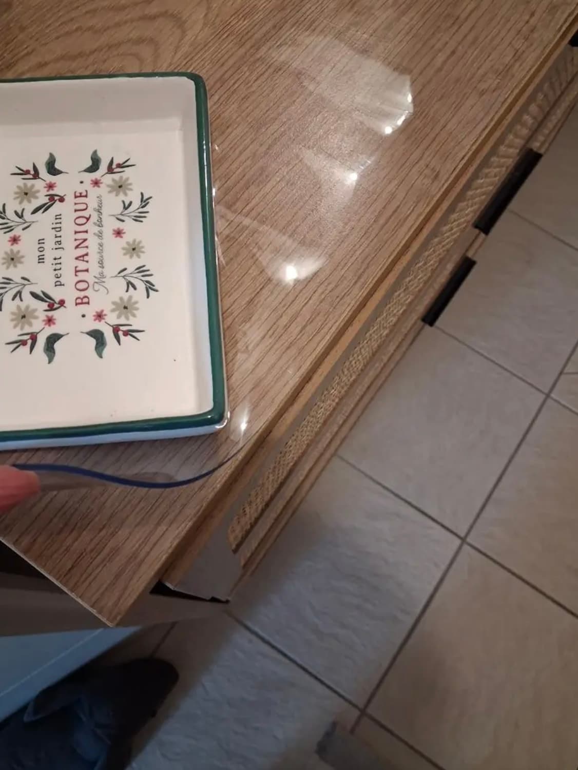 Corner of an oak chest of drawers with a decorative tray; the hand holds the edge of the clear overlay