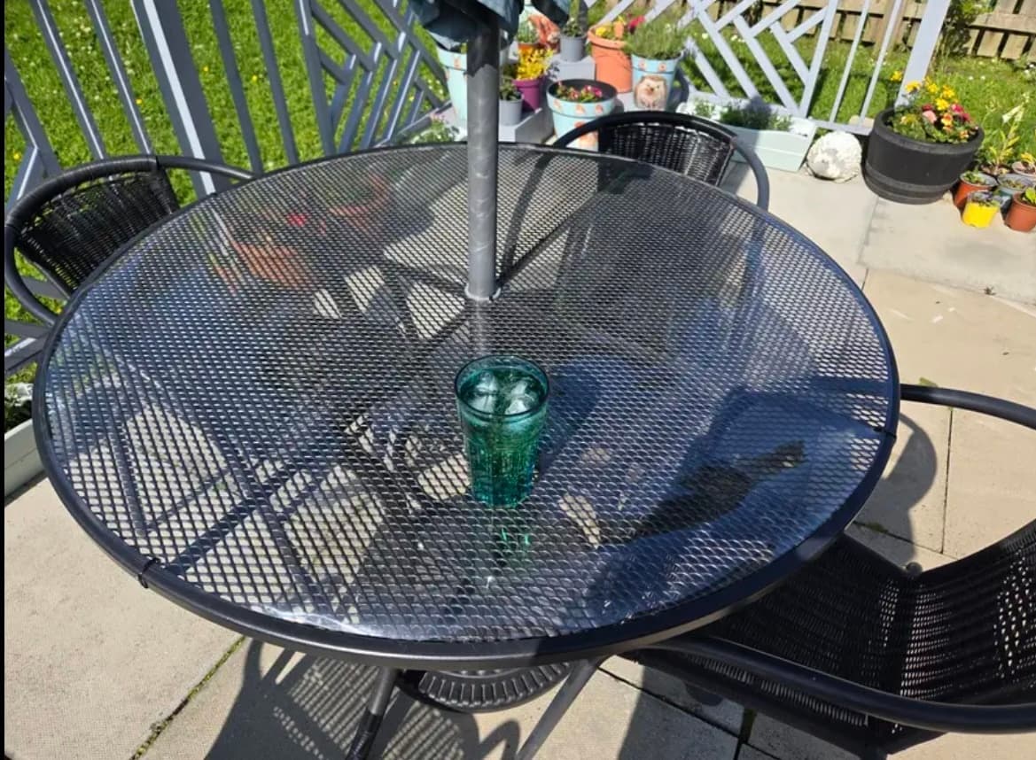 A mat on a round table on the terrace, a glass of drink in the middle, pots of flowers around