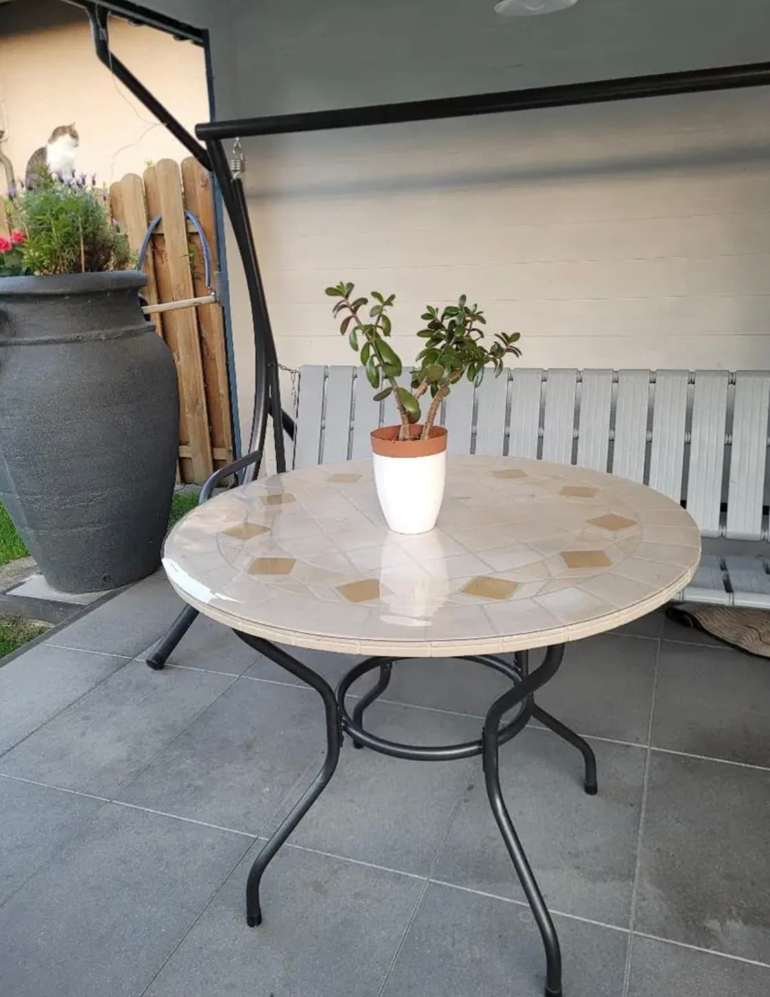 A round table with a mosaic top on the terrace, a crassula flower pot on the mat