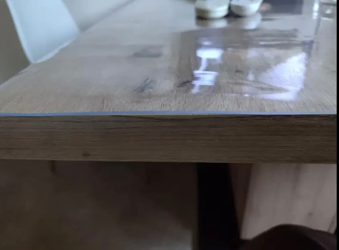 Close-up of the edge of the table: the thin edge of the mat ends flush above the wood
