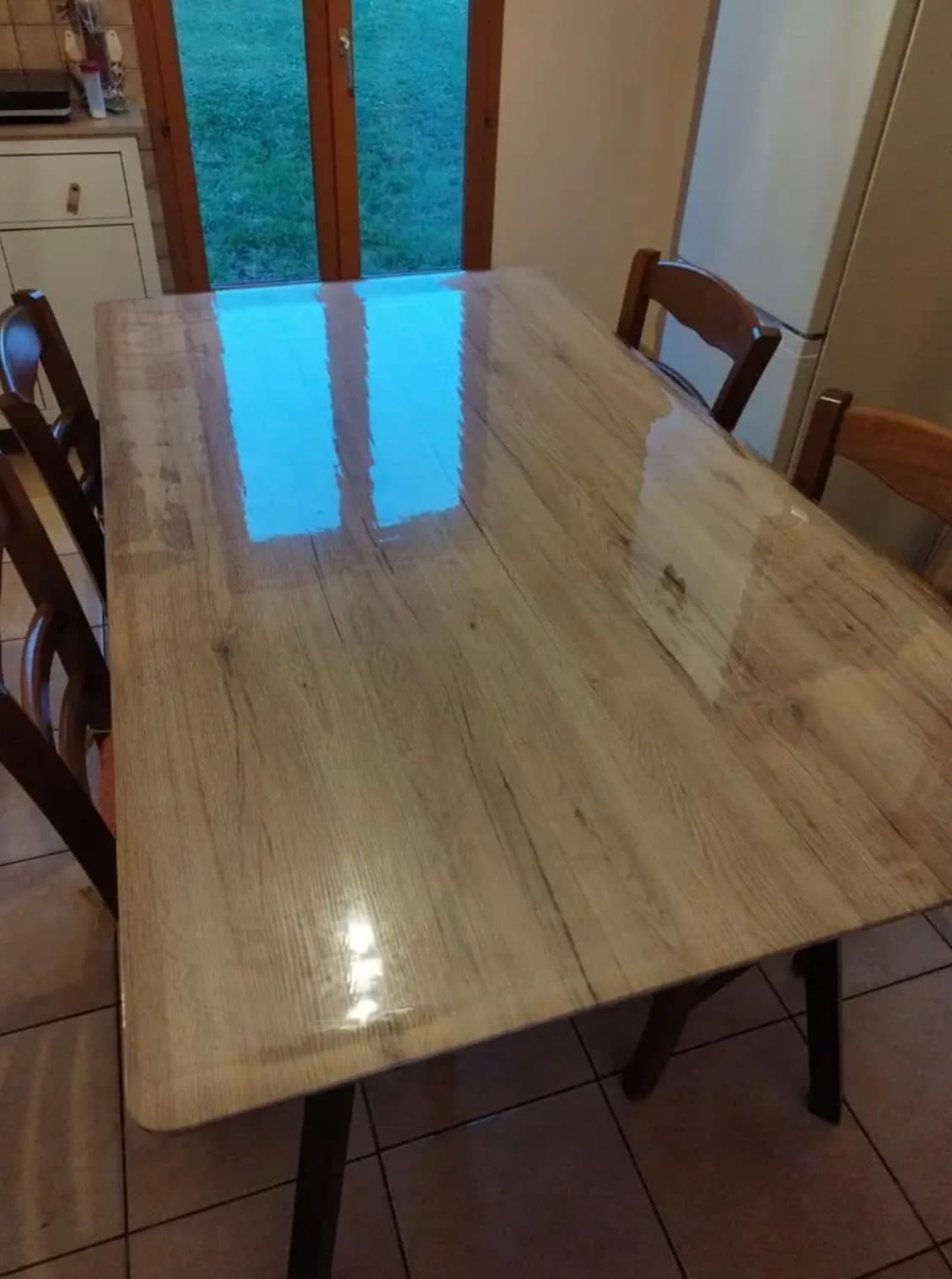 Light oak kitchen table; the door to the garden is reflected in the mat