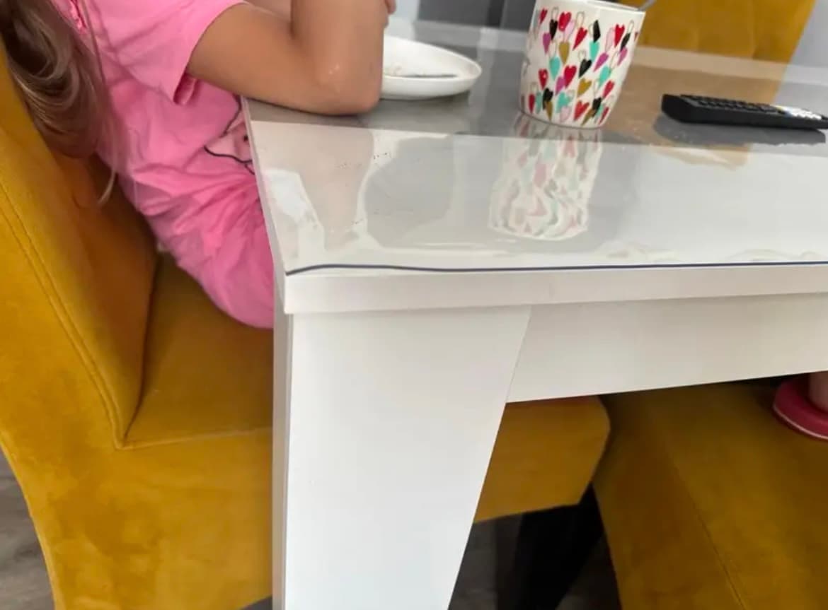 A child at a white table with mustard chairs; the edge of the mat runs along the edge of the countertop