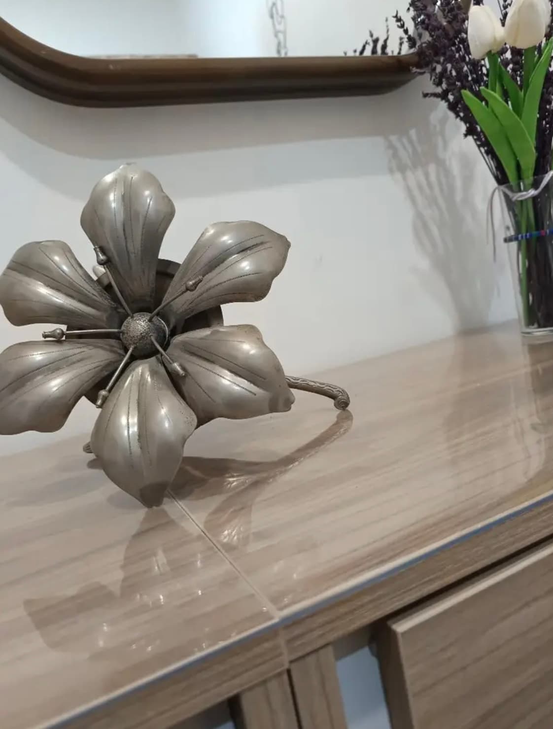 Bright chest of drawers with metal floral decoration and tulips; table top covered with soft glass