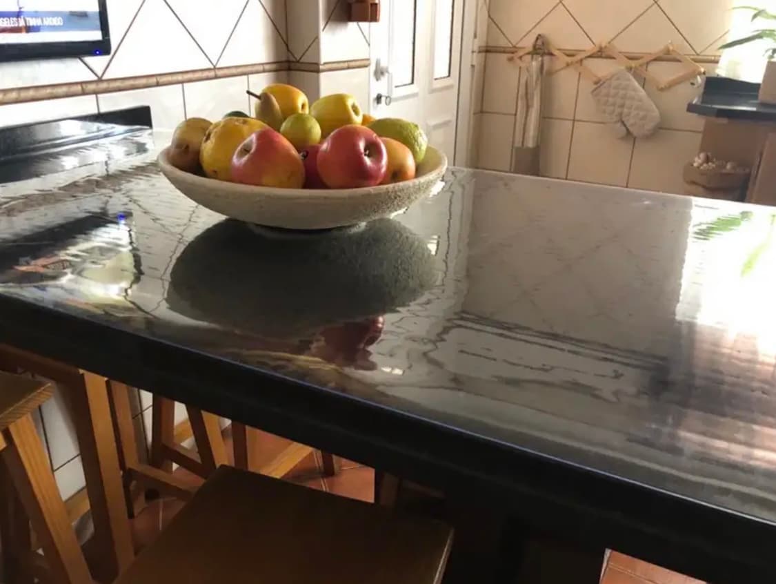 Kitchen peninsula with a marble-patterned countertop - a bowl of apples and pears stands on a mat